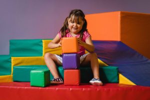 happy girl playing with big colourful blocks