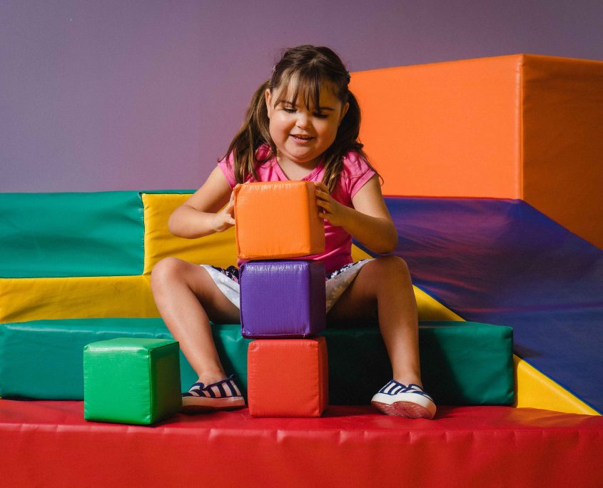 happy girl playing with big colourful blocks